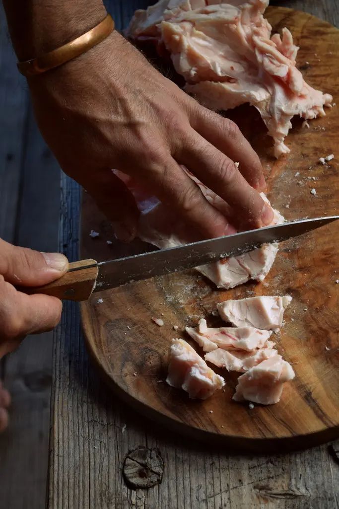 Close-up of a lady cutting chunks of 100% grass-fed tallow on a wooden board, showcasing Mirath Beauty’s natural skincare ingredient sourced in Lebanon for nourishing and biocompatible sunscreen