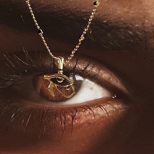 Close-up of a woman’s eye with a gold necklace and evil eye pendant aligned with her iris, representing Tallow’s protective barrier for the skin, inspired by ancestral Arabic protection rituals.