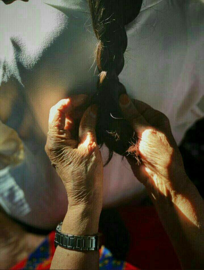 Mirath Beauty — elderly woman’s hands with chipped red nail polish braiding long dark hair, symbolizing ancestral beauty rituals and Lebanese heritage behind our tallow skincare and natural botanicals