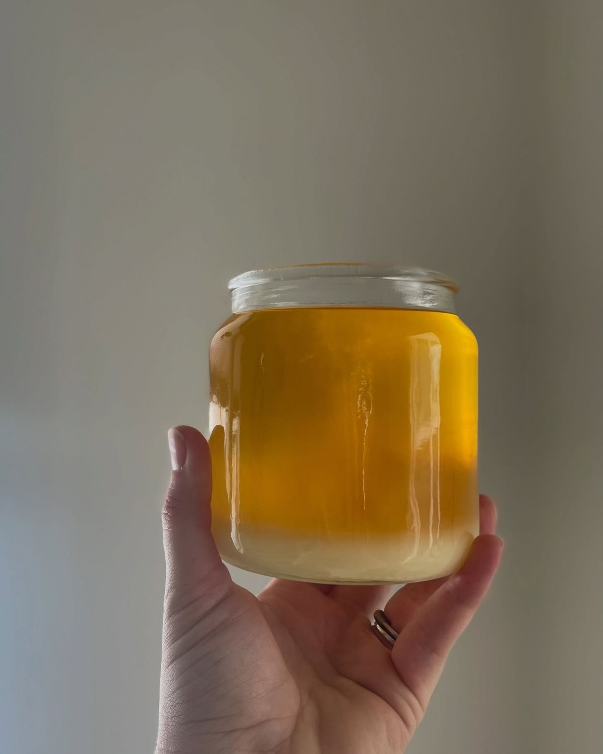 Transparent glass jar filled with Mirath beauty tallow in its raw, golden form — half solid, half liquid — highlighting the purity, richness, and ancestral skincare power of tallow compared to conventional moisturizers